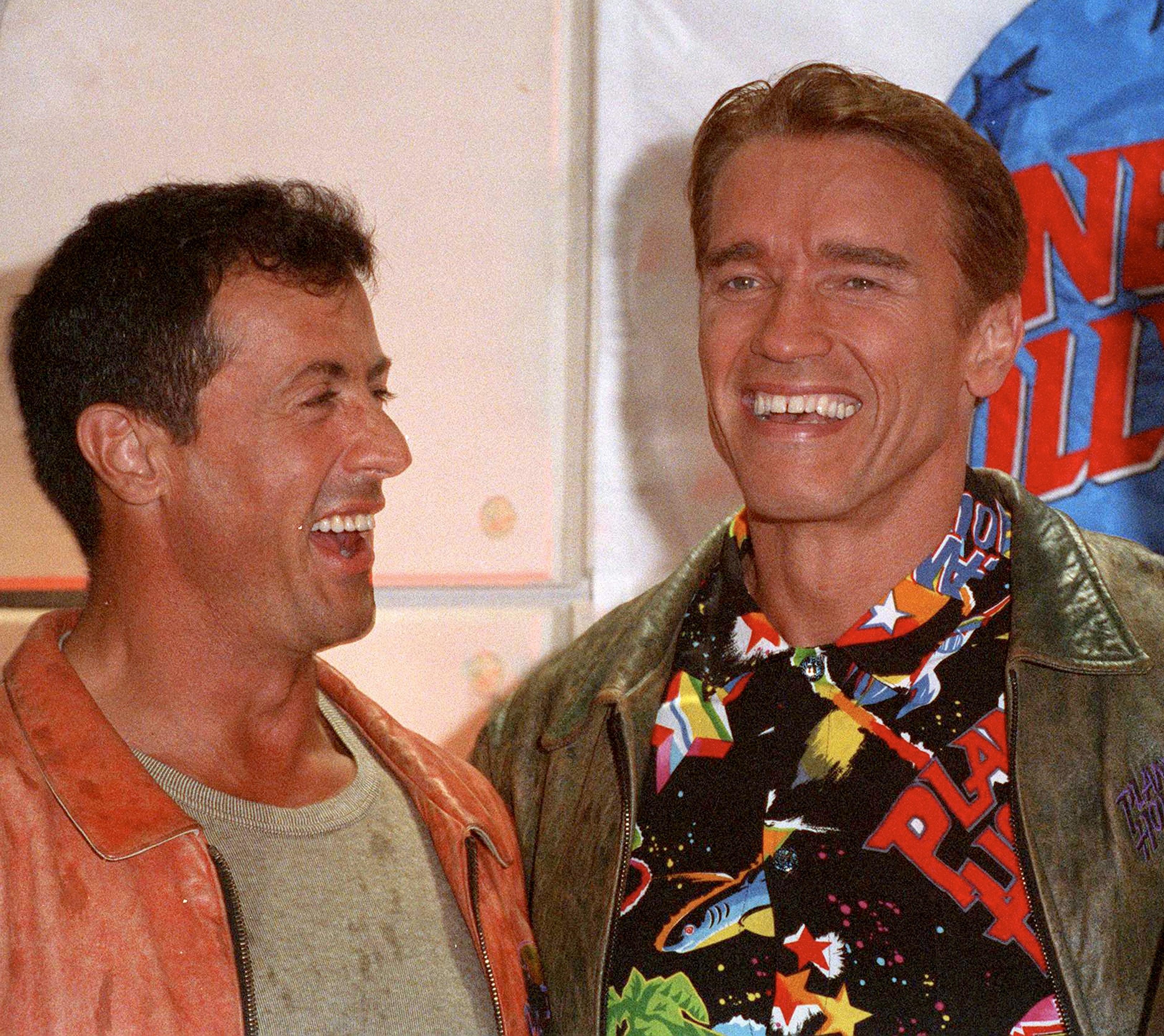 Two men in casual attire smile and stand together, capturing a candid moment