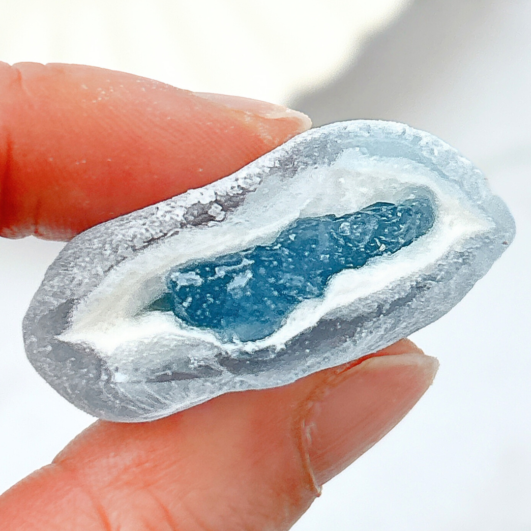 手で持たれた青い宝石のような形をした氷菓子。