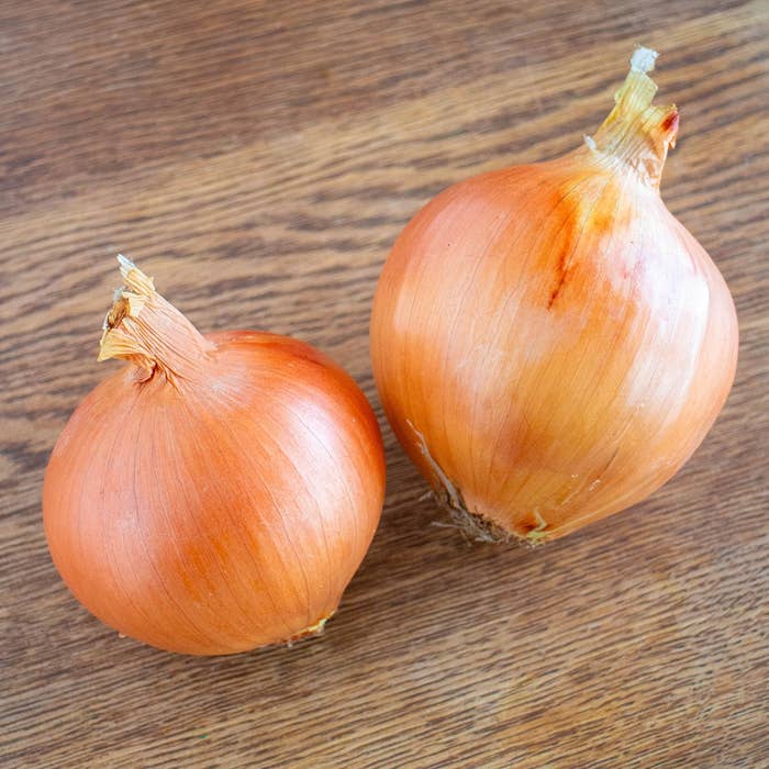 2つの玉ねぎが木製のテーブルの上に置かれています。