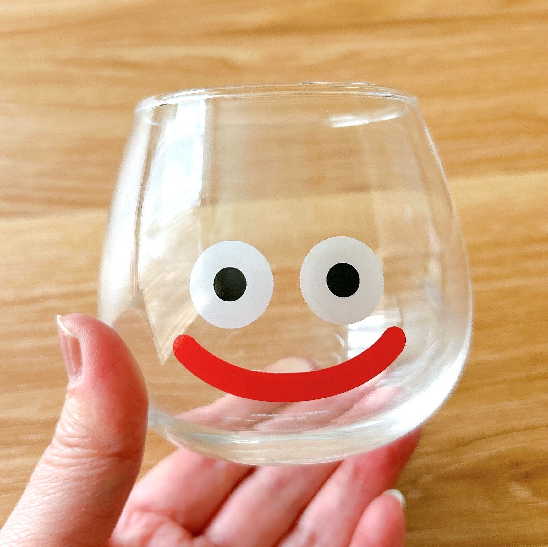 ユーモラスな顔が描かれたガラスのコップを手に持つ。