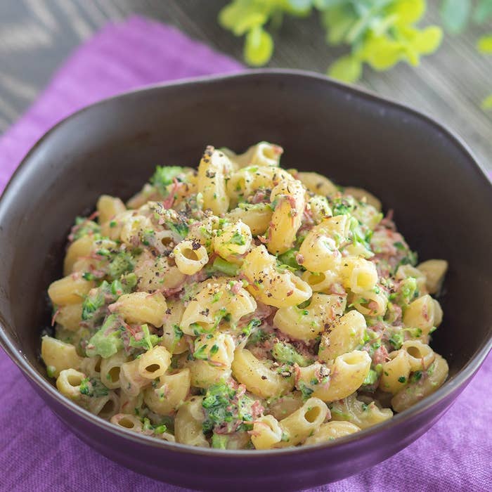 ボウルに盛られたマカロニサラダ、刻んだ野菜と調味料がトッピングされています。