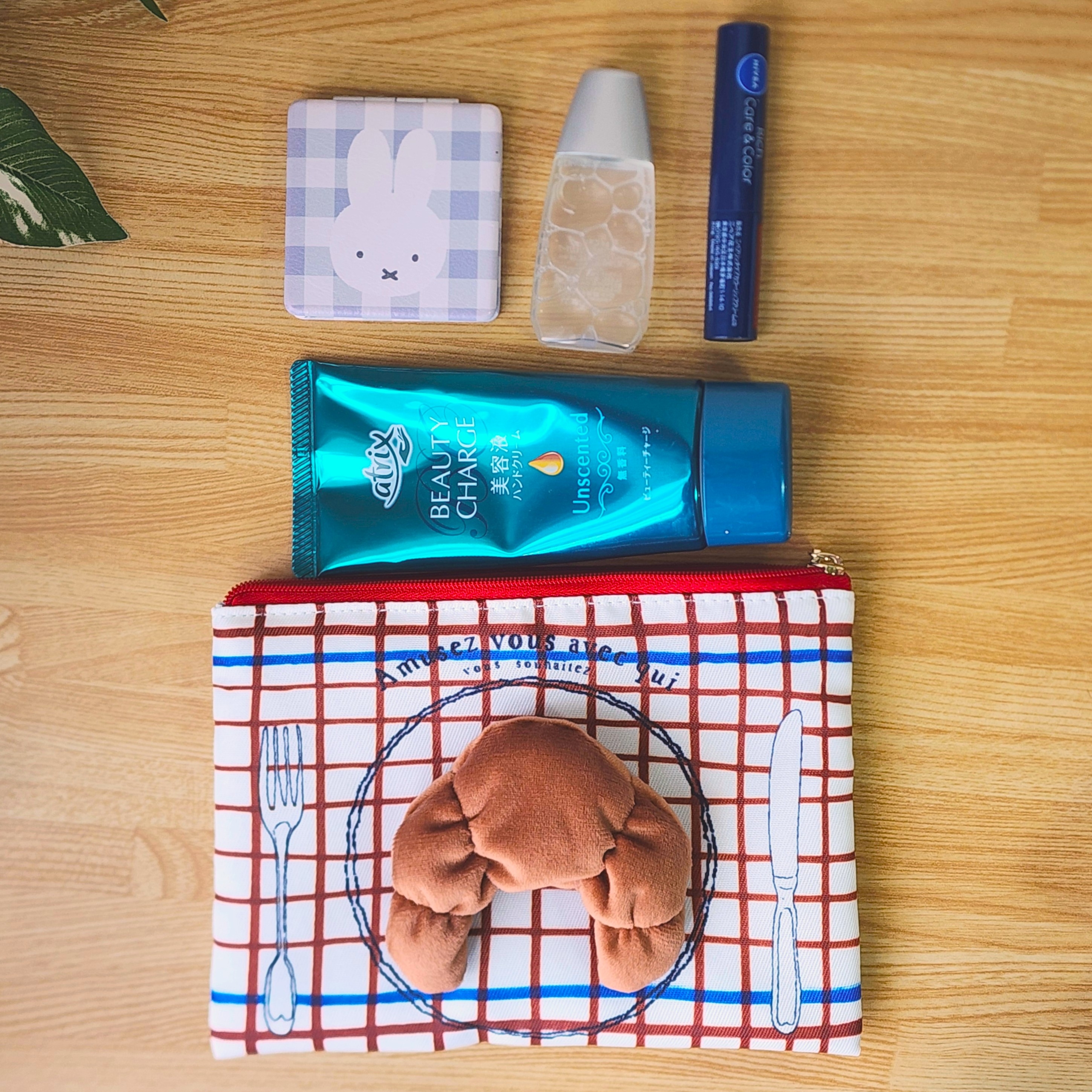 テーブルに化粧ポーチとボトル、パウダーコンパクトが並べられた風景。