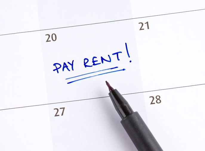 Calendar close-up with a "Pay Rent!" reminder written in blue ink on the 20th