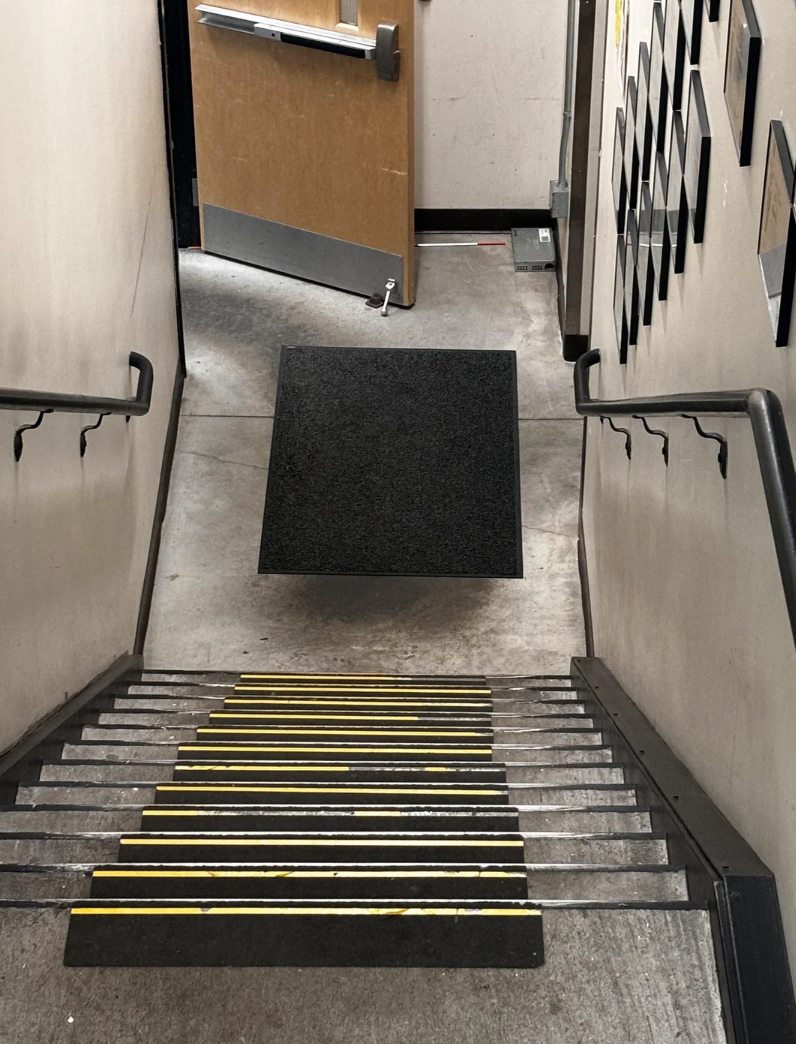 A stairway with a door open at the bottom is blocked by a floating black platform, obstructing access