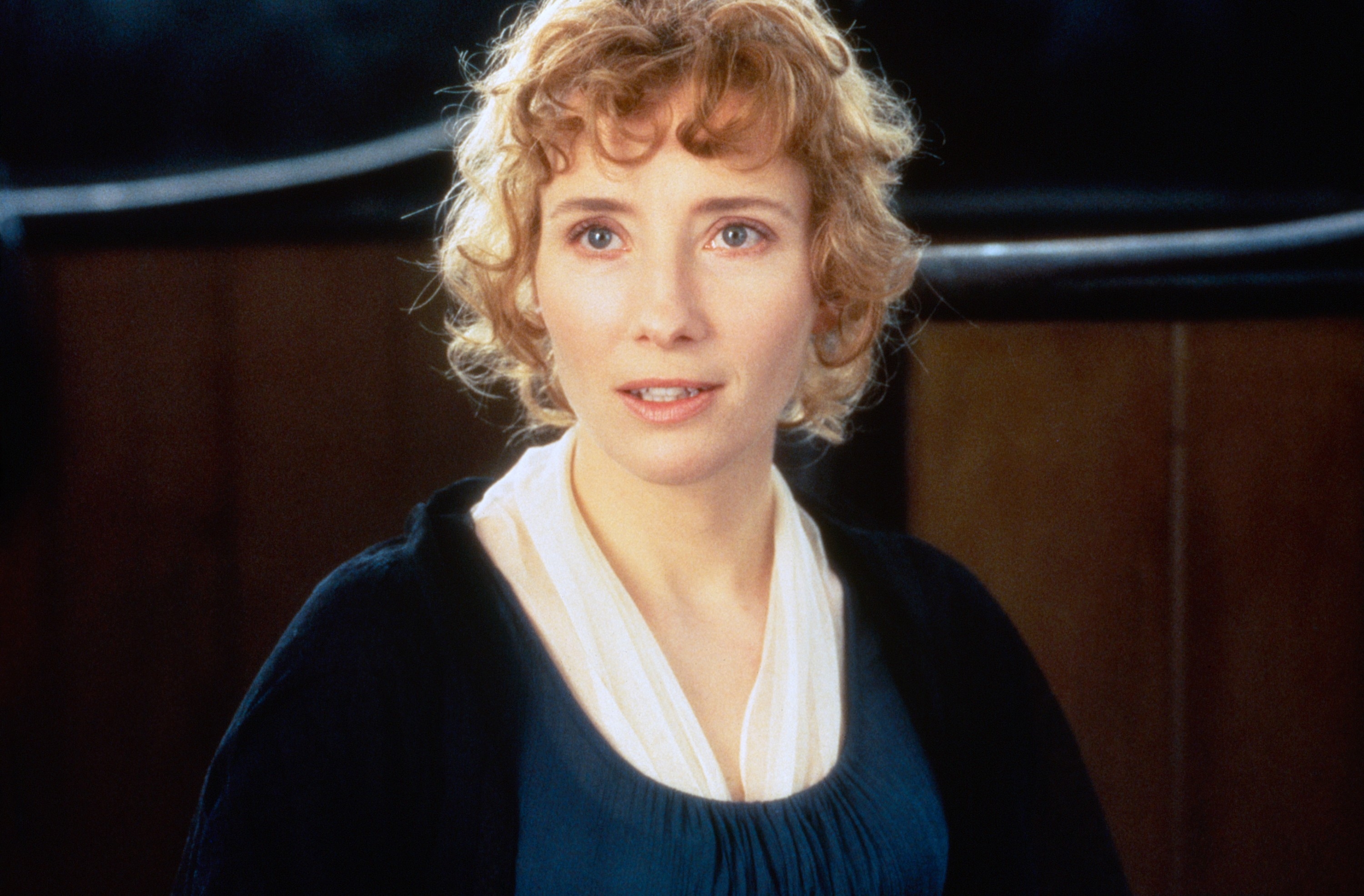 Person with curly hair wearing period-style clothing, looking thoughtfully forward