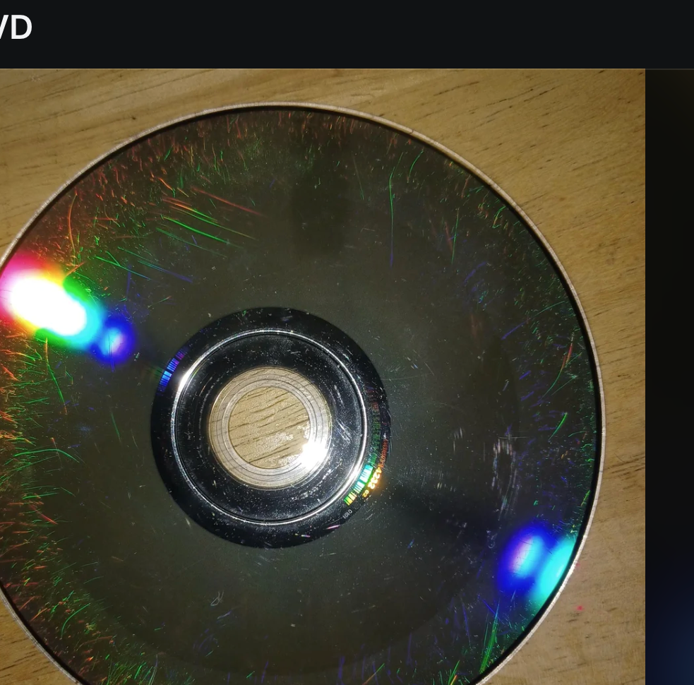 A scratched DVD is displayed on a computer screen showing various menu and post details