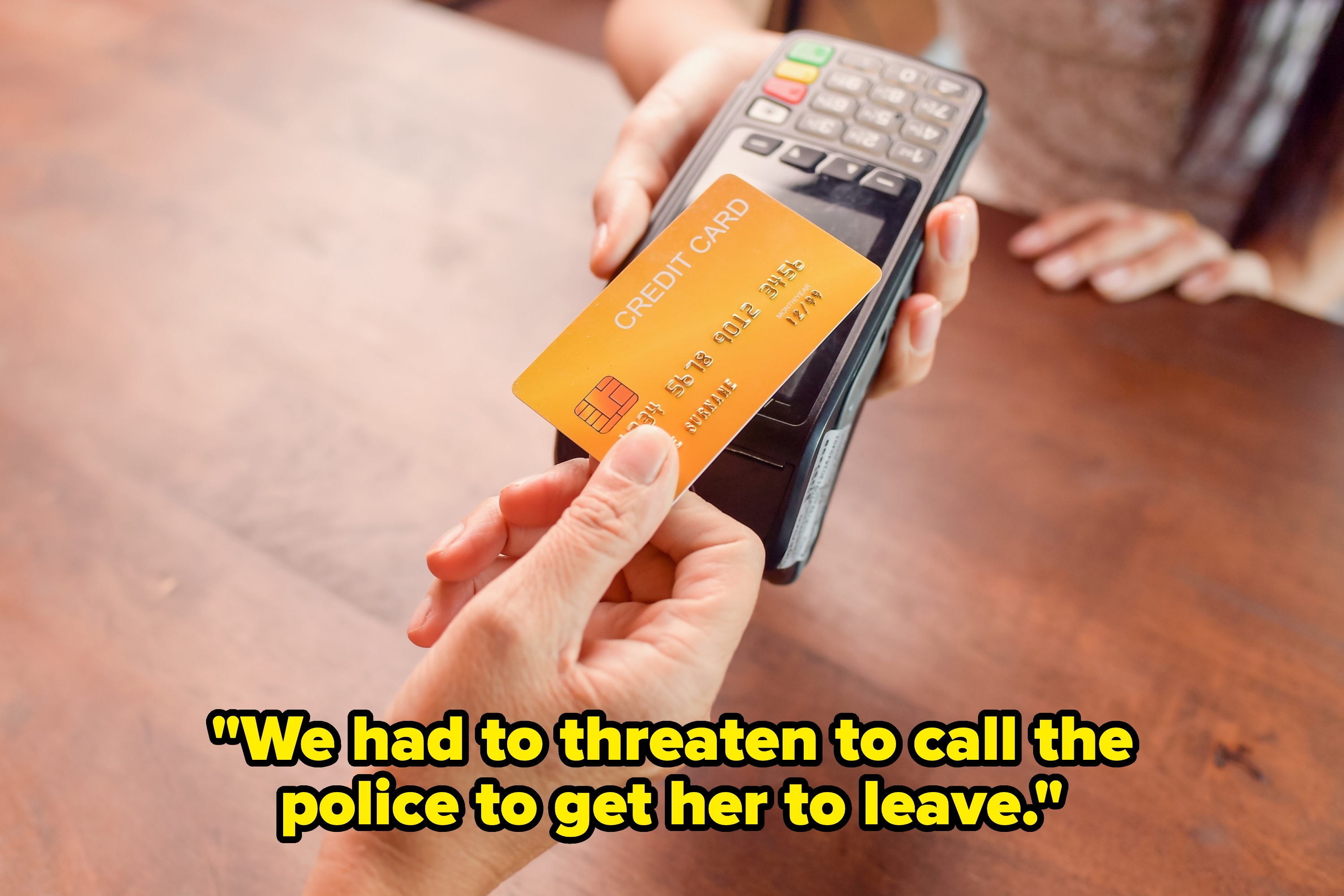 Close-up of two hands holding a credit card over a card reader, indicating a contactless payment transaction