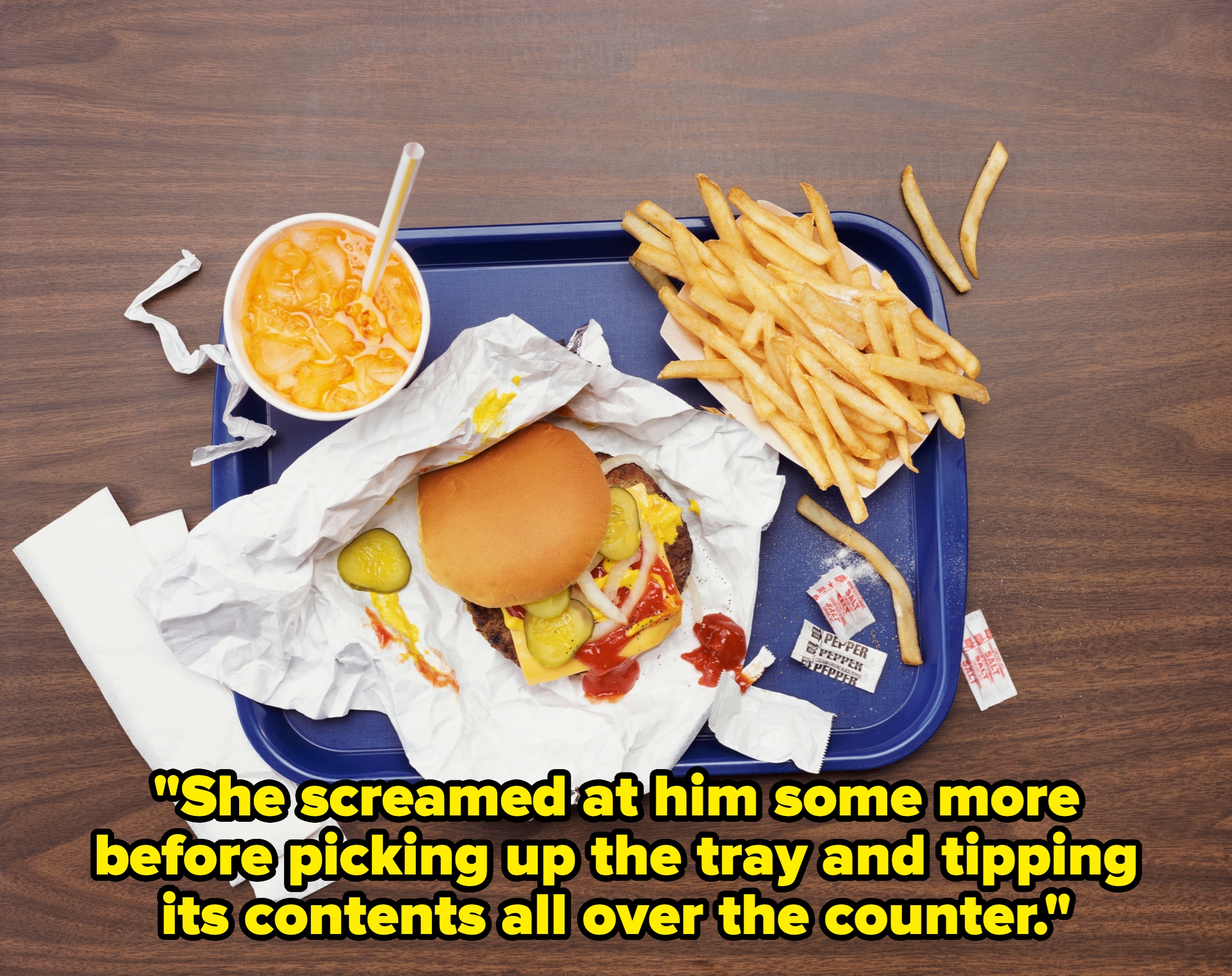 Fast food meal with a wrapped burger, a cup of mac and cheese, fries on a tray, with napkins and condiments nearby