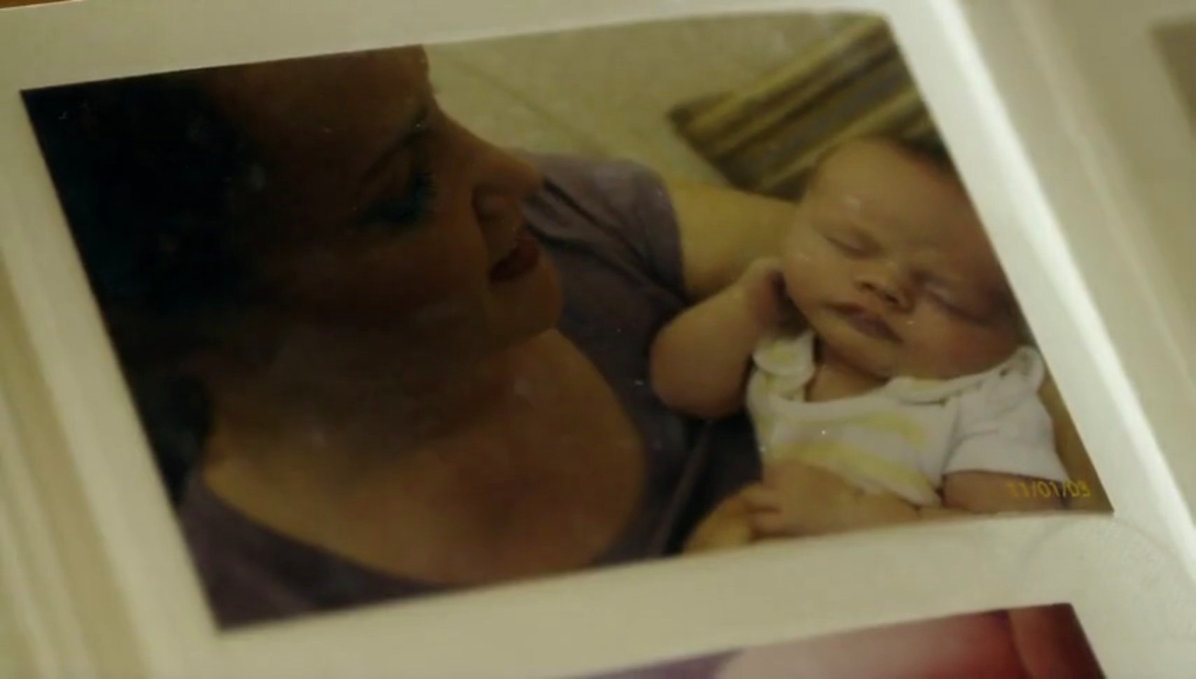 A person is holding a sleeping baby, captured in a warm, candid moment, inside a photo album