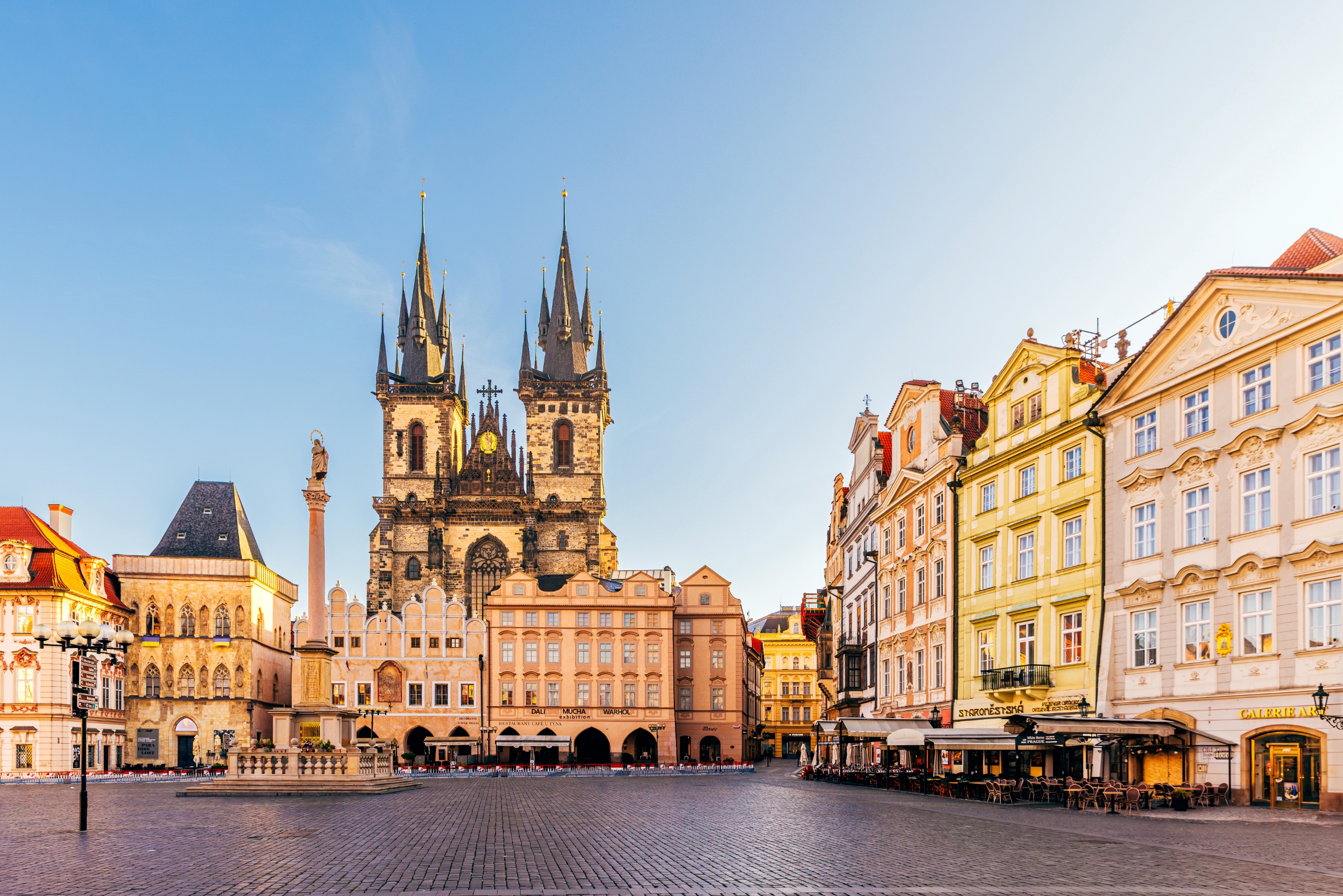 Historic town square with Gothic church, colorful buildings, and cobblestone pavement under a clear sky, creating a picturesque European travel scene