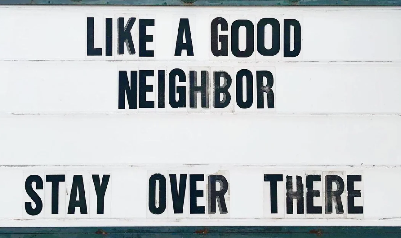 Marquee sign with text: "LIKE A GOOD NEIGHBOR STAY OVER THERE," humorously mimicking a familiar slogan