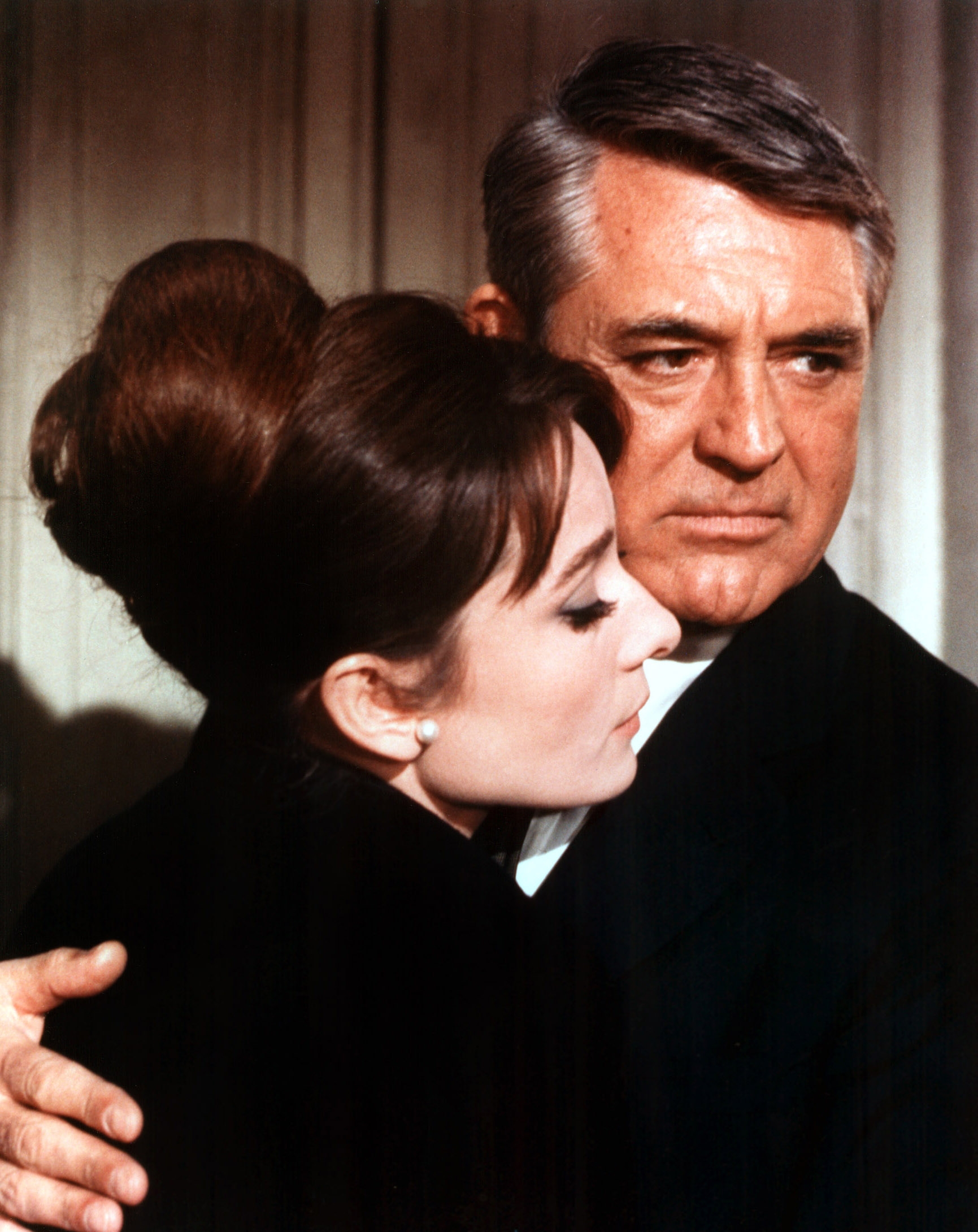 A man and woman embrace; she rests her head on his chest. Both are in formal attire