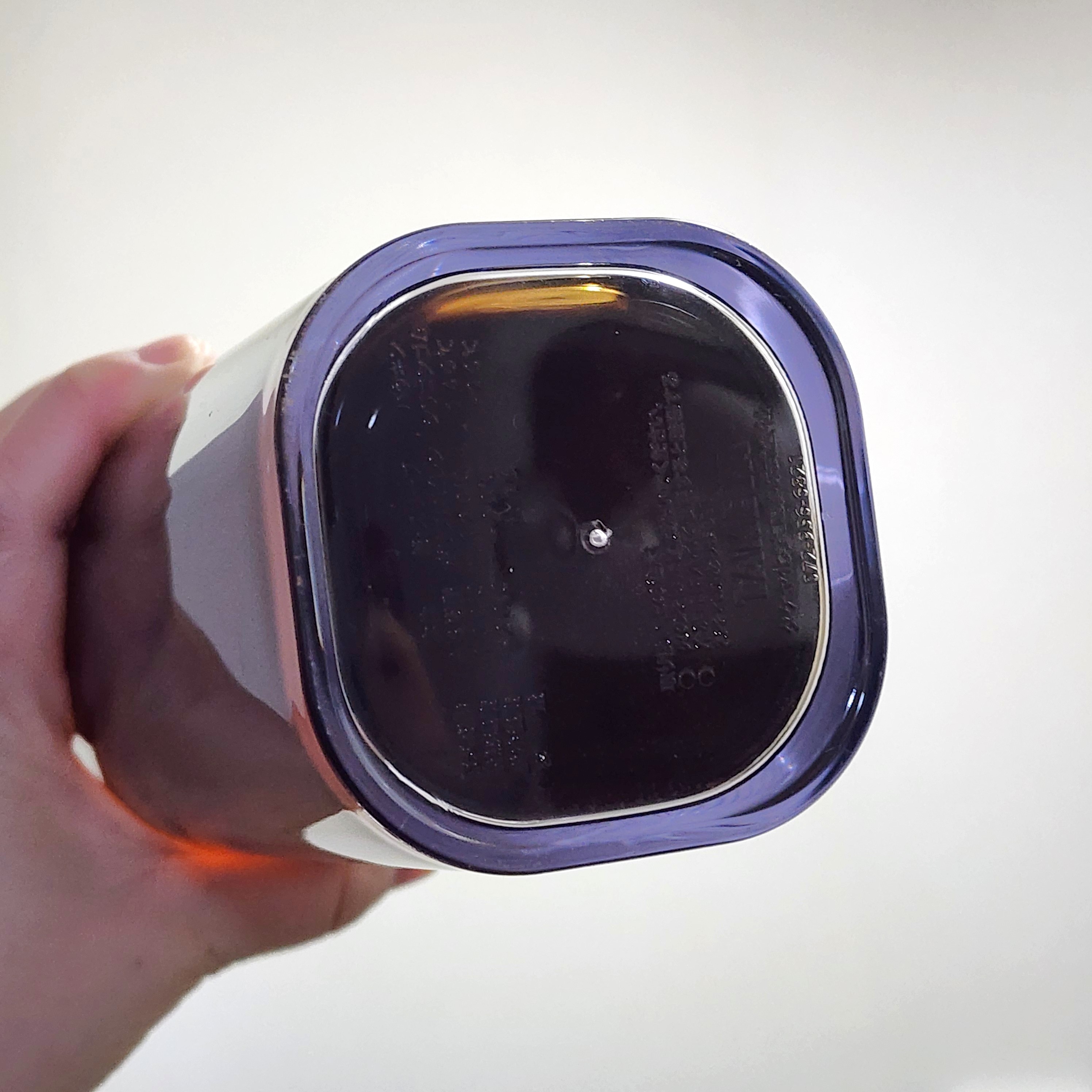 人が手に持っている容器の底面。容器にはテキストがあり、詳細な情報が刻まれています。