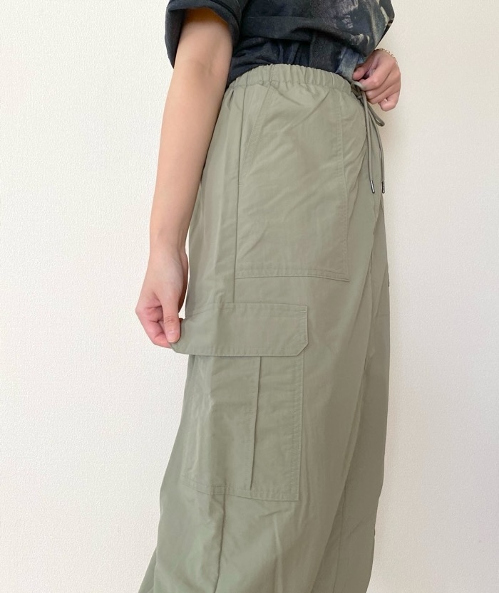 Person in a black t-shirt and loose, high-waisted pants with large pockets, showcasing a casual and relaxed fashion style