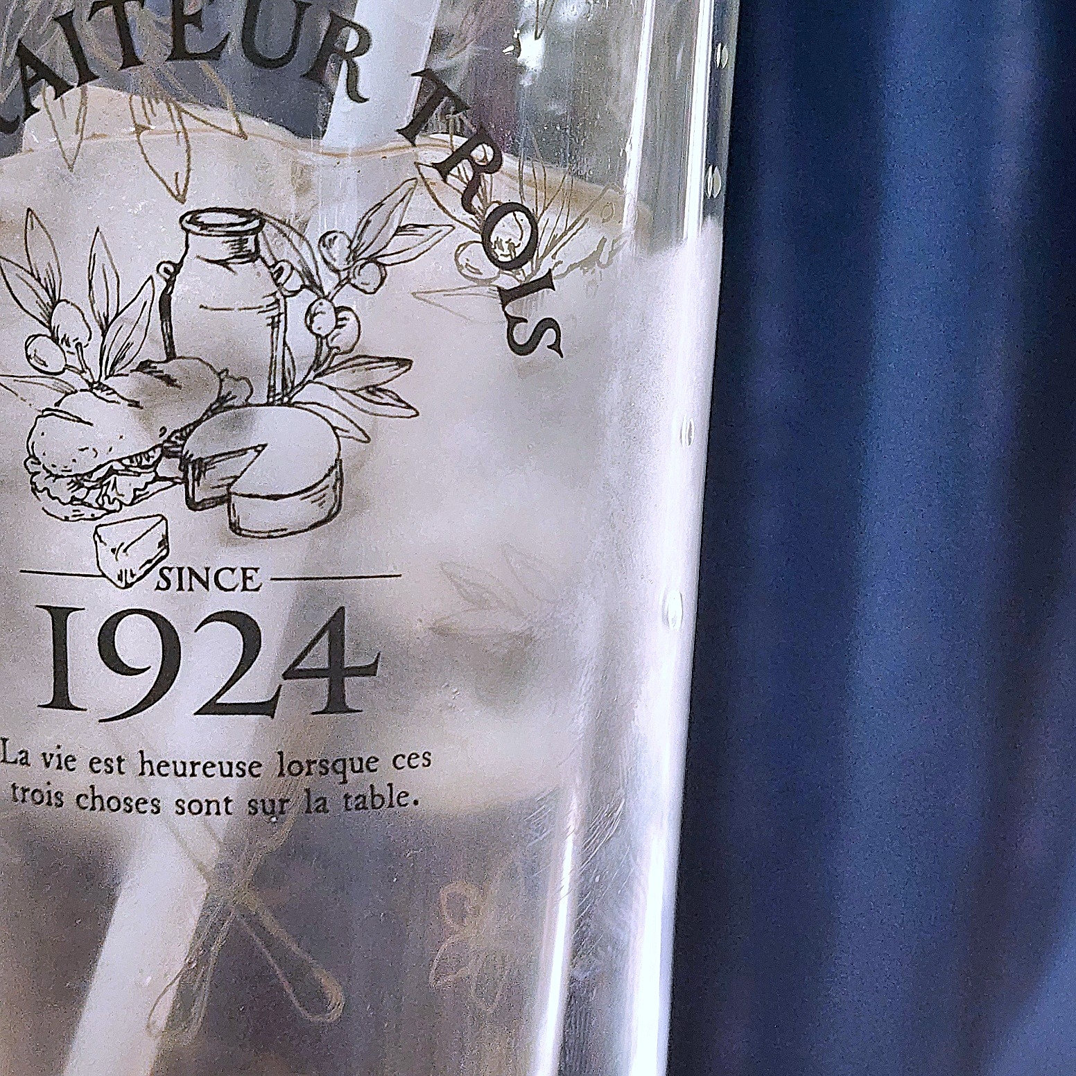 ビンテージスタイルのガラス瓶に、1924年に遡るフランス語のテキストと食べ物のイラストが描かれている。