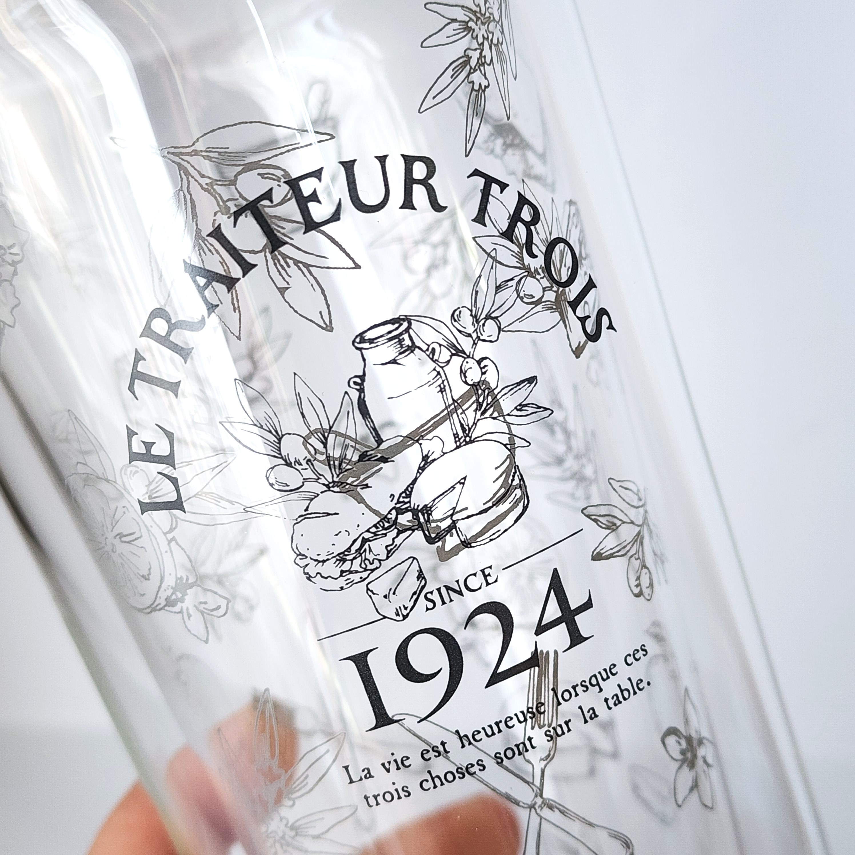透明なグラスに「LE TRAITEUR TROIS」と1924年の文字が印刷されています。その他にフランス語の装飾文字とイラストがあります。
