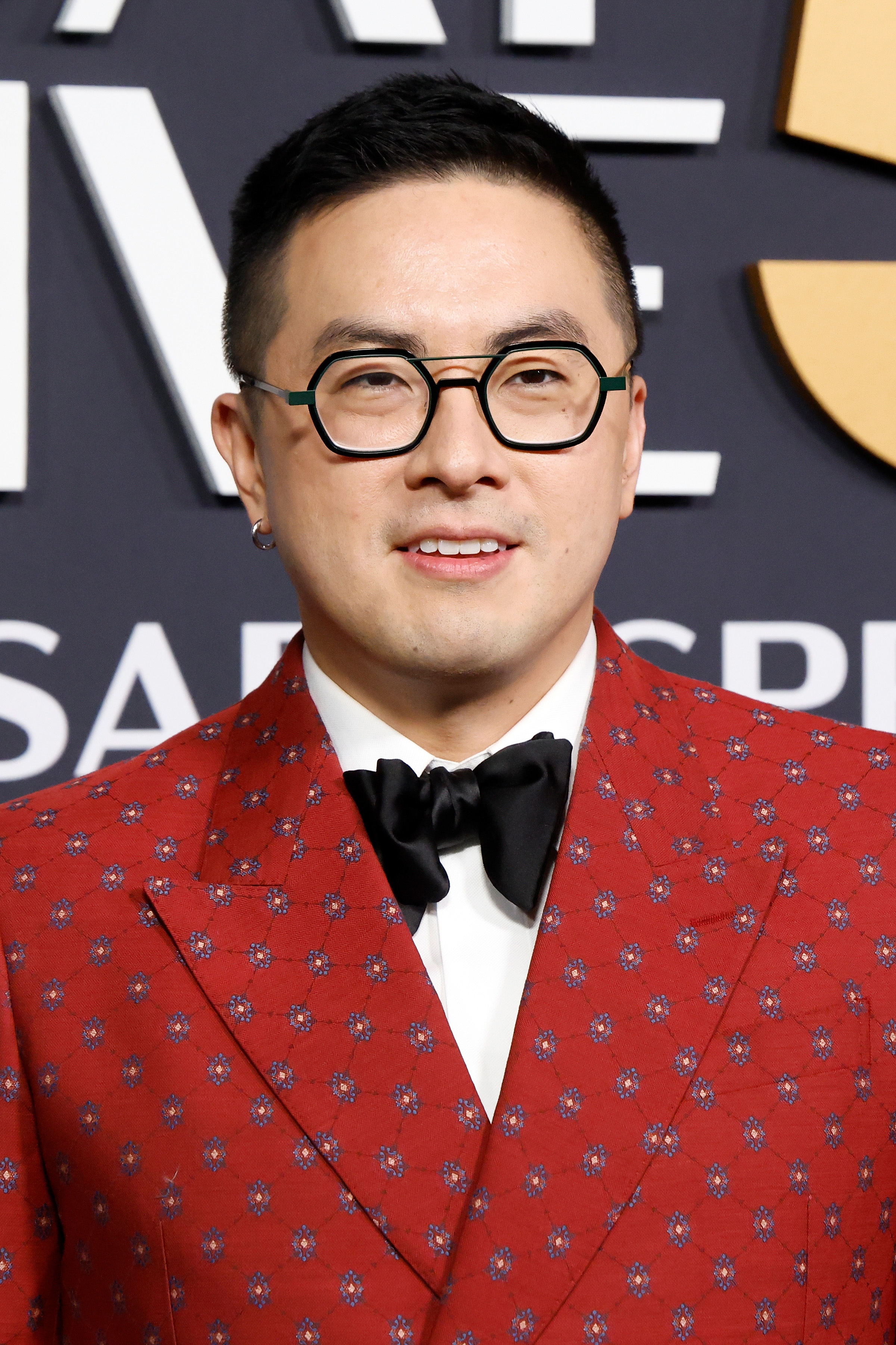 Bowen Yang wearing a patterned jacket with a bow tie, posing at an event
