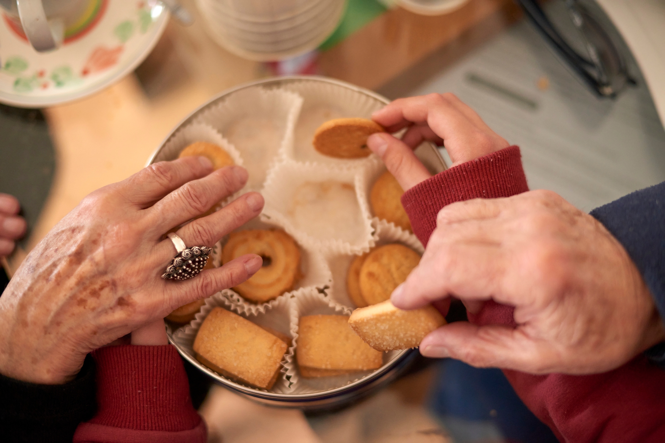 Hender som strekker seg etter diverse informasjonskapsler i et tinn, med dekorative papirforinger, og skaper et koselig og herlig snack -delingsøyeblikk