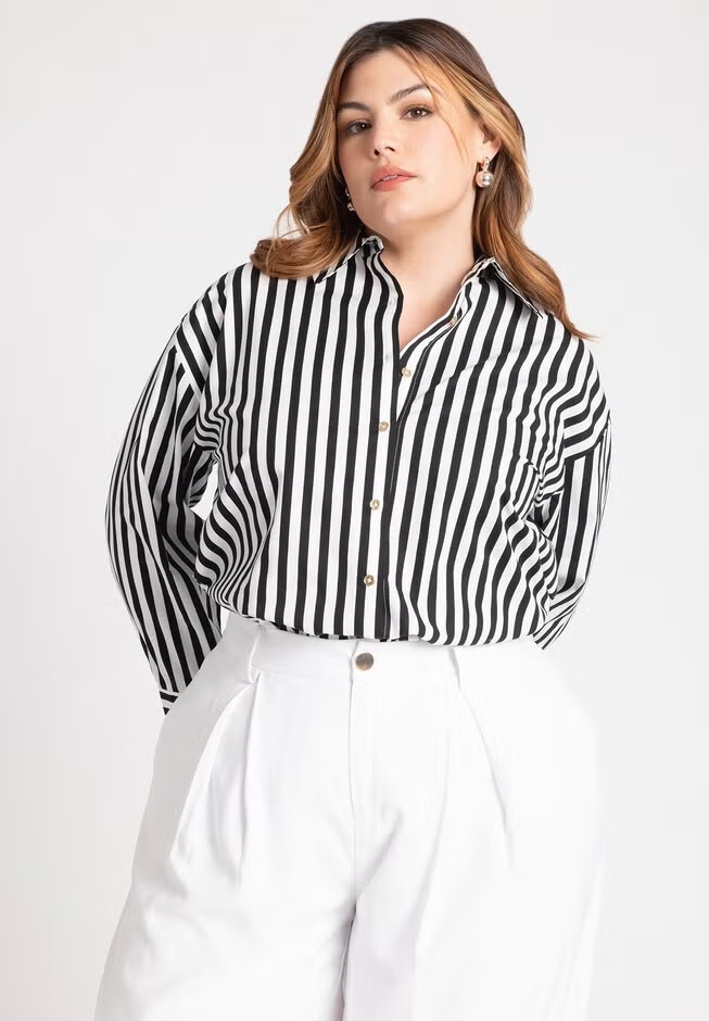 Person wearing a striped button-up shirt and high-waisted wide-leg trousers, posing confidently