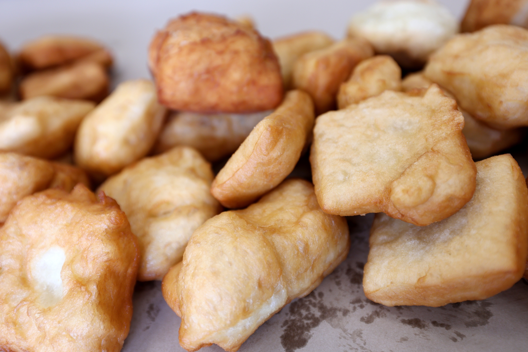 Close-up of several pieces of fried dough, with a golden, fluffy texture on a flat surface