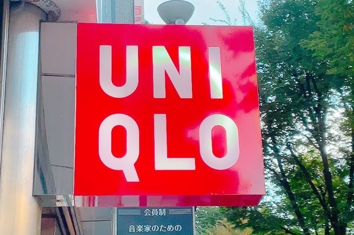 Uniqlo store sign with bold letters on a bright background, positioned next to a tree