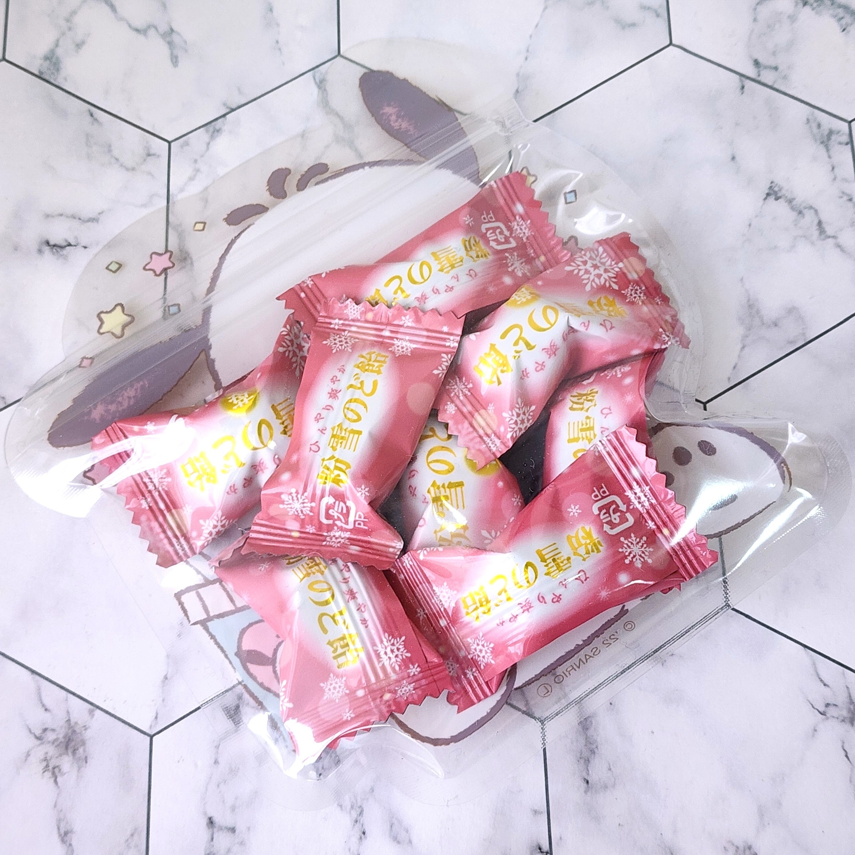 透明な袋に入った数個のピンクの包み紙のキャンディ。和菓子のイメージで包装されています。