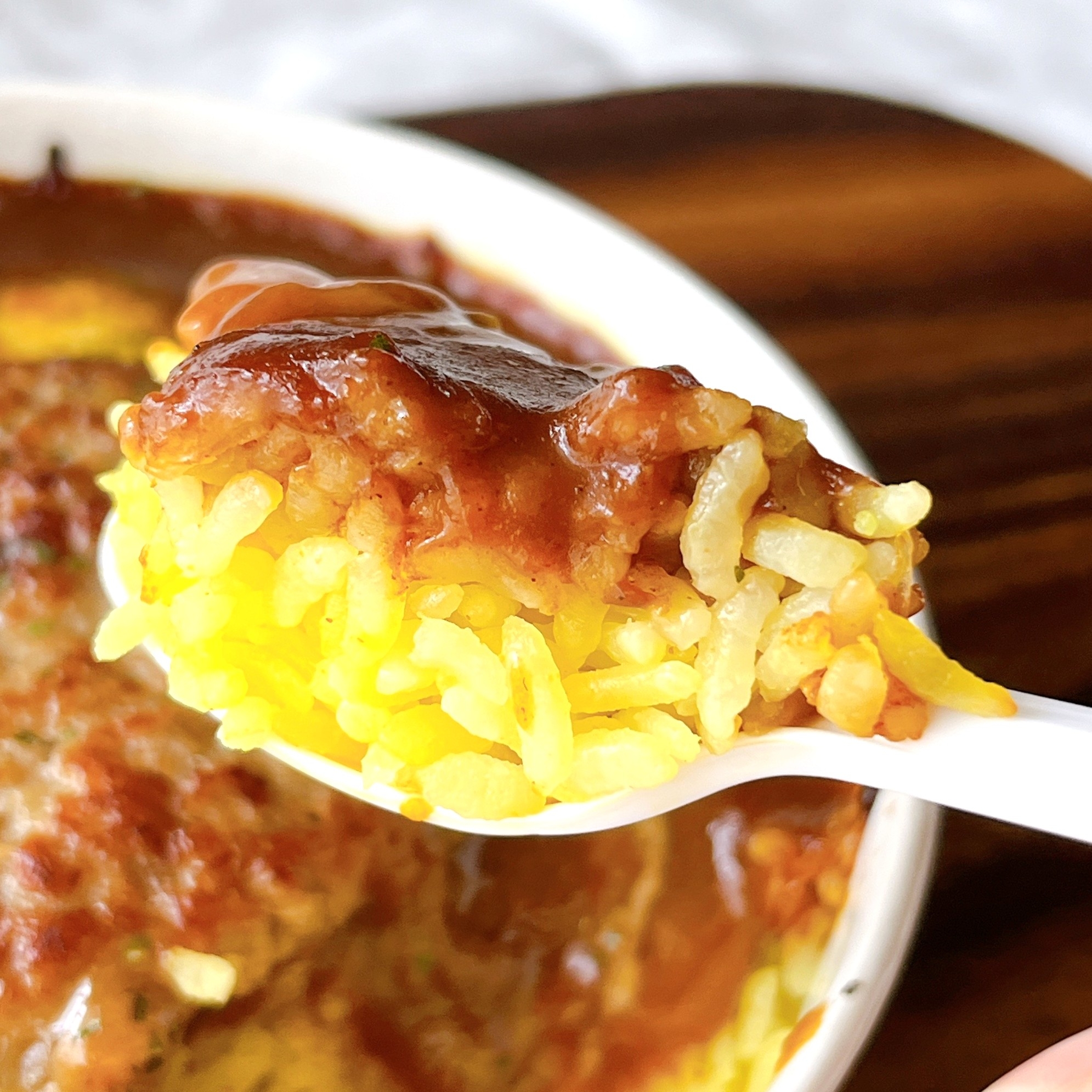 スプーンで持ち上げたカレーライスのクローズアップ。食欲をそそるシーン。