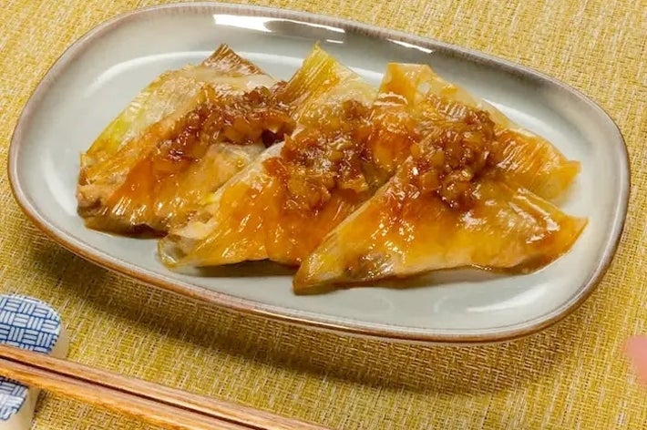 魚の料理が皿に盛られている。上にはソースがかかっており、添えられた箸が見える。