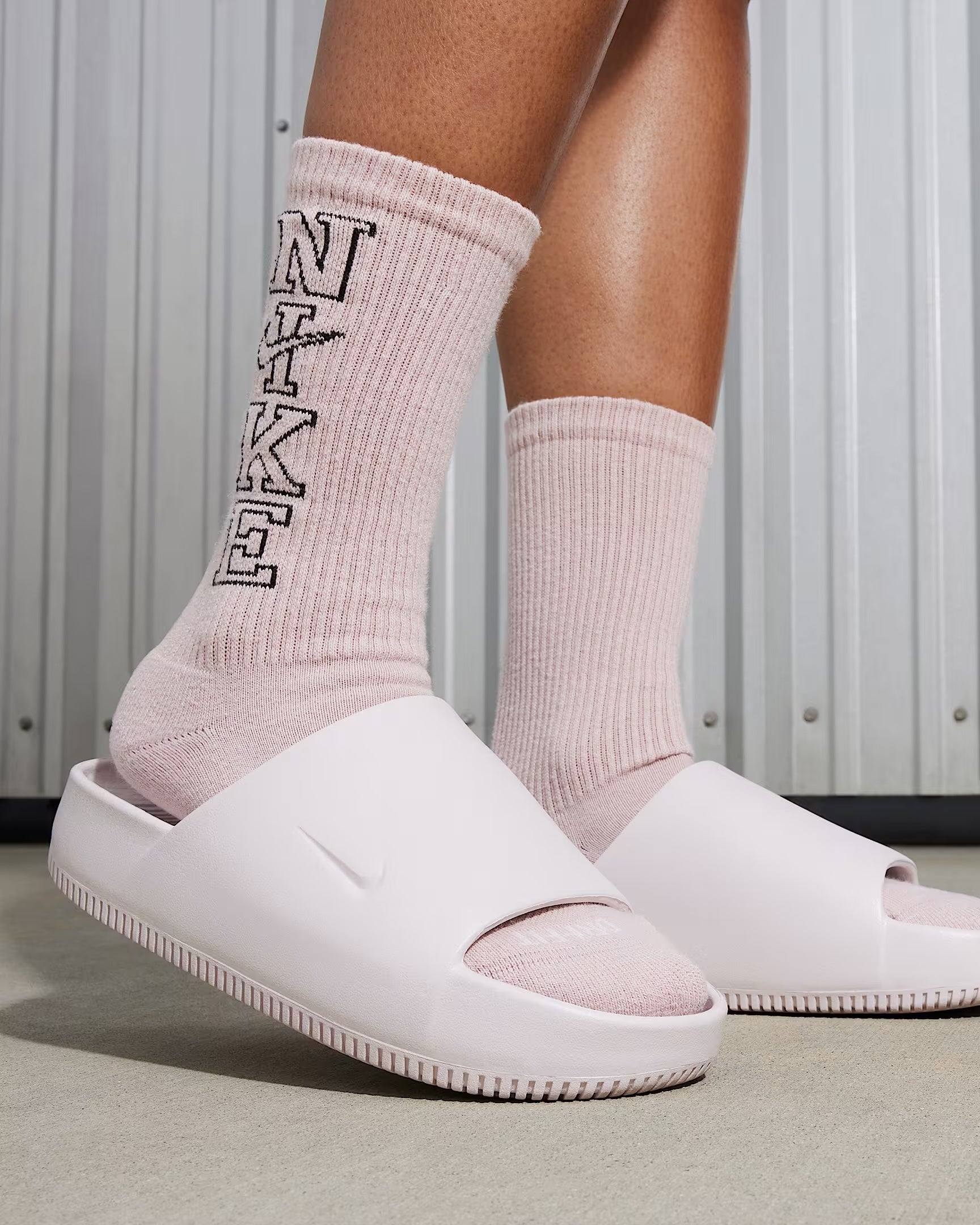 Orang yang mengenakan slide nike di atas kaus kaki tebal
