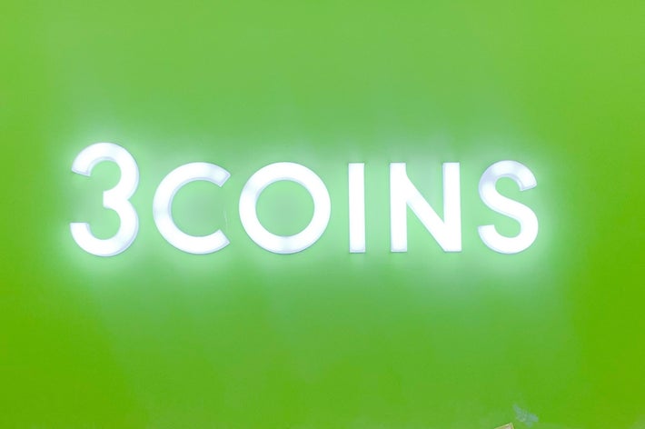 店舗の看板に「3COINS」と書かれている。店内には割引のポスターが見える。