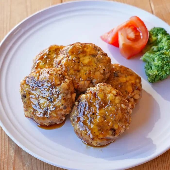 皿の上にハンバーグ4つとブロッコリー、トマトが並んでいる。