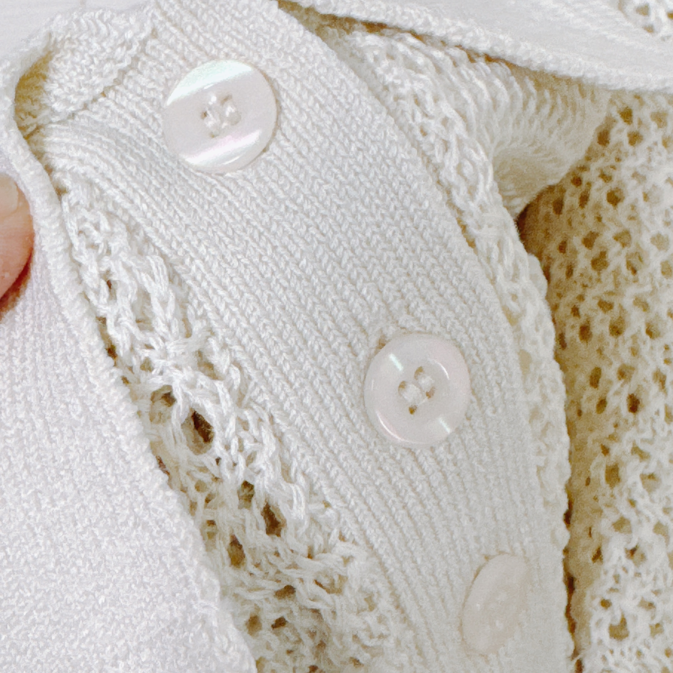 Close-up of a textured knit fabric with buttons, showcasing intricate crochet and ribbed knitting details