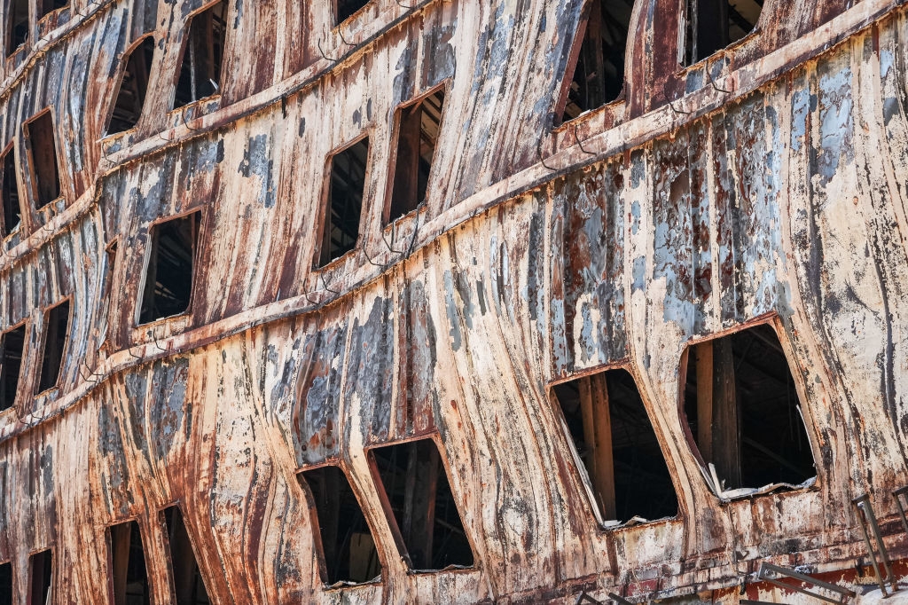 Rusty ship hull with square windows, showing weathered and decayed metal, illustrating abandonment and the passage of time