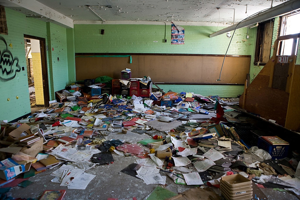 Room filled with scattered books and papers, indicating disarray and neglect. Walls show signs of peeling paint