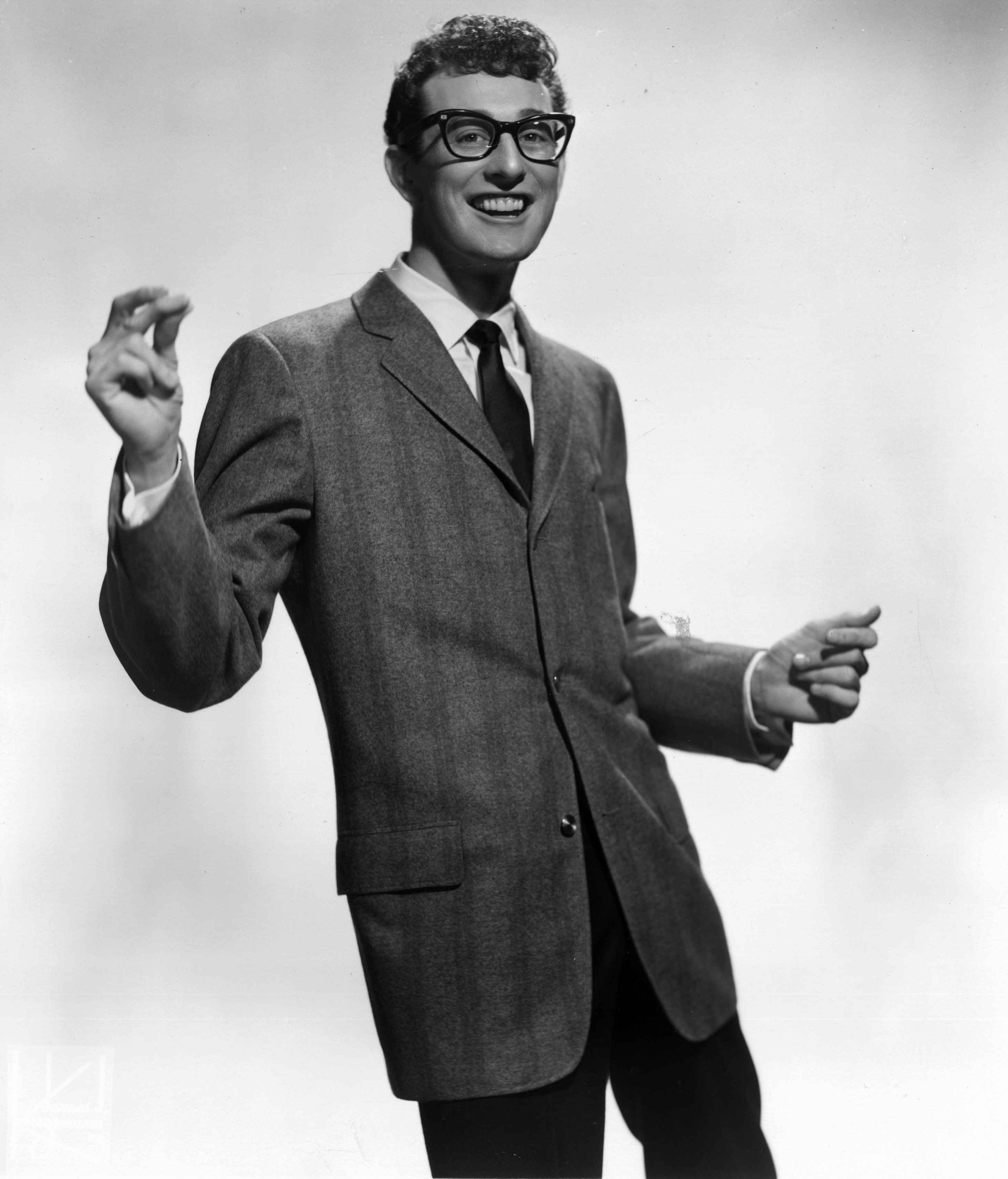 Person wearing a tailored suit and tie, striking a dynamic pose with a cheerful expression