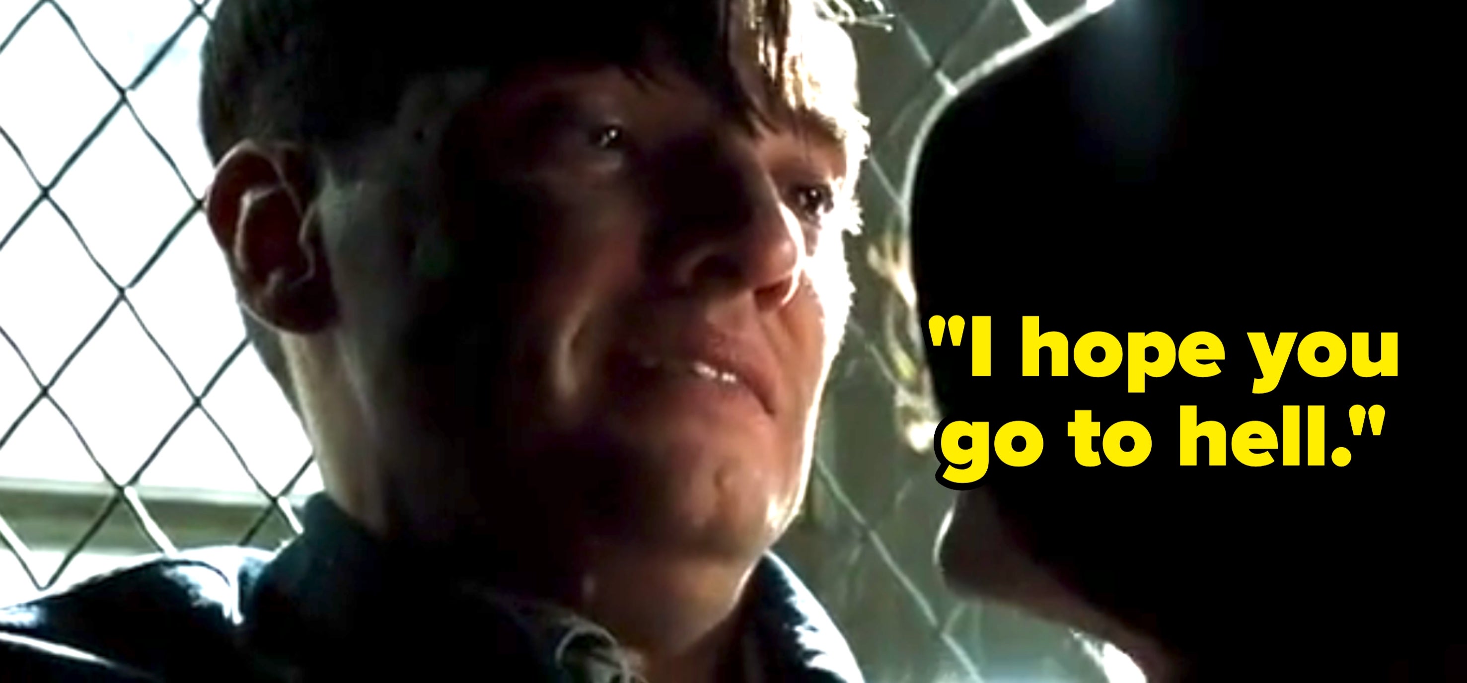 A man and a woman are speaking closely near a fence, with the man's expression appearing emotional and intense