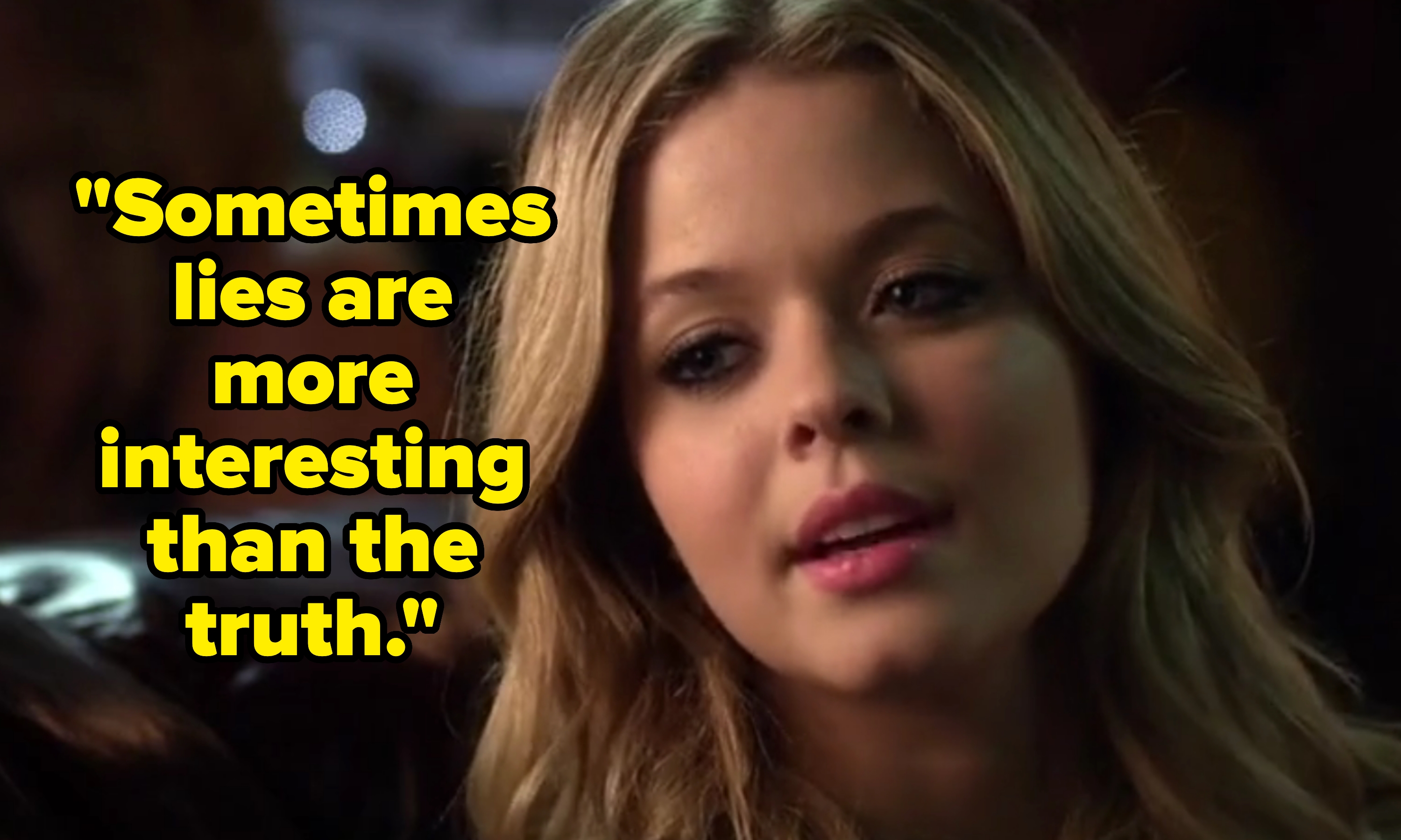 Person with long wavy hair looking to the side, seated indoors against a blurred background