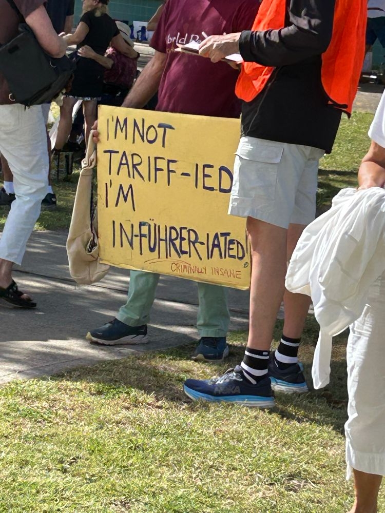 Protestor holding a sign reading, "I'm not tariff-ied, I'm in-fuhrer-iated!" with "Criminally insane" written underneath