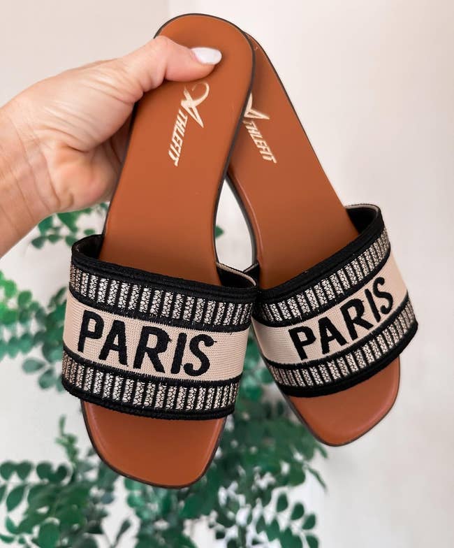 Close-up of reviewer manus  holding a brace  of descent  sandals with 