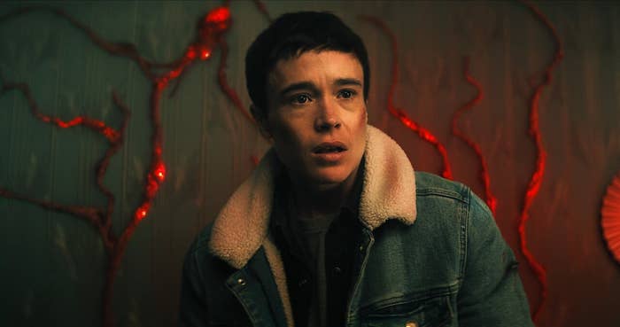 Persona con chaqueta de jean con forro de lana, parpadea en un ambiente oscuro con luces rojas difusas en el fondo