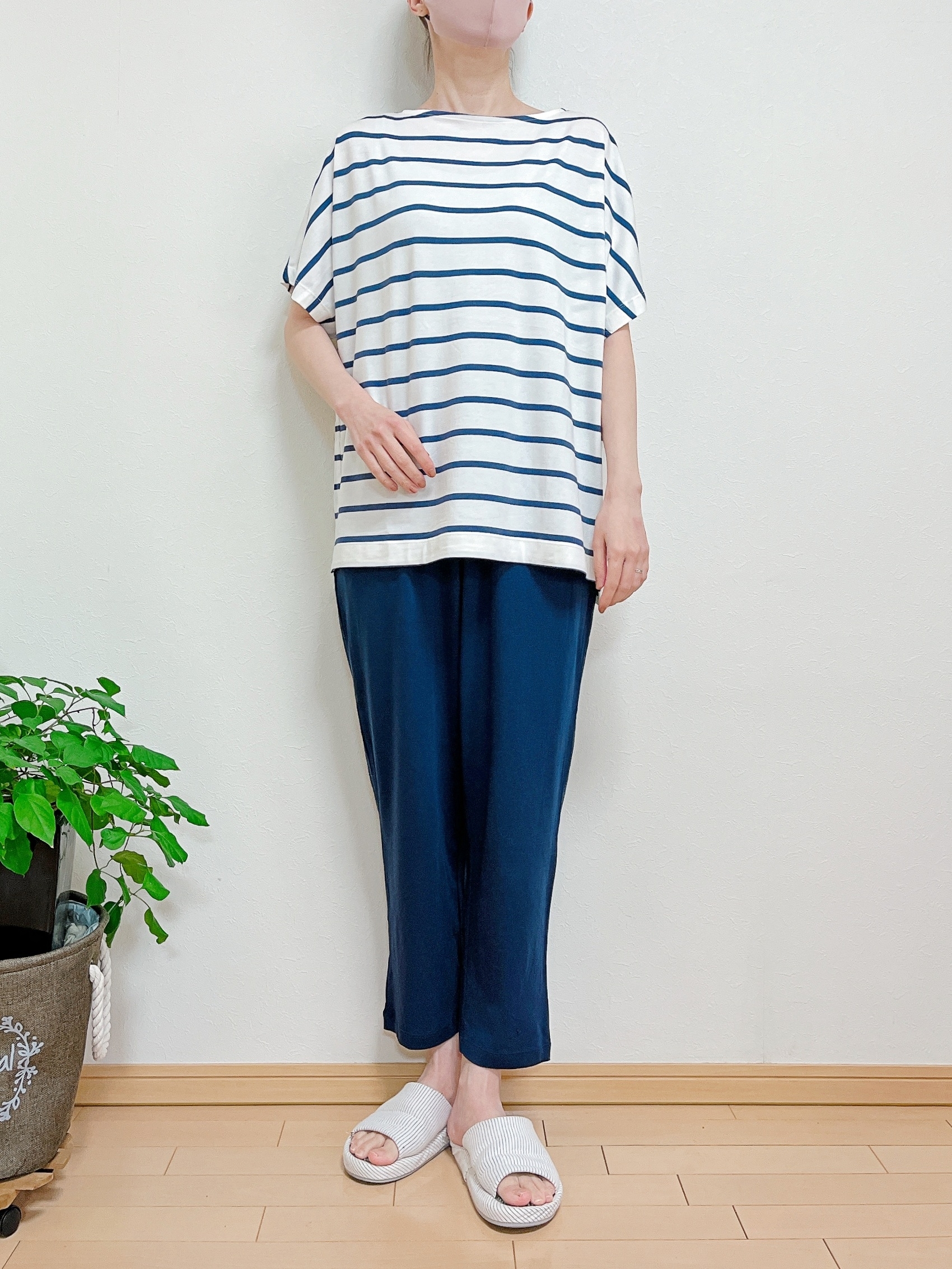 ゆったりとしたボーダーシャツとリラックスパンツを着た人物が写っています。カジュアルな室内スタイルを示しています。