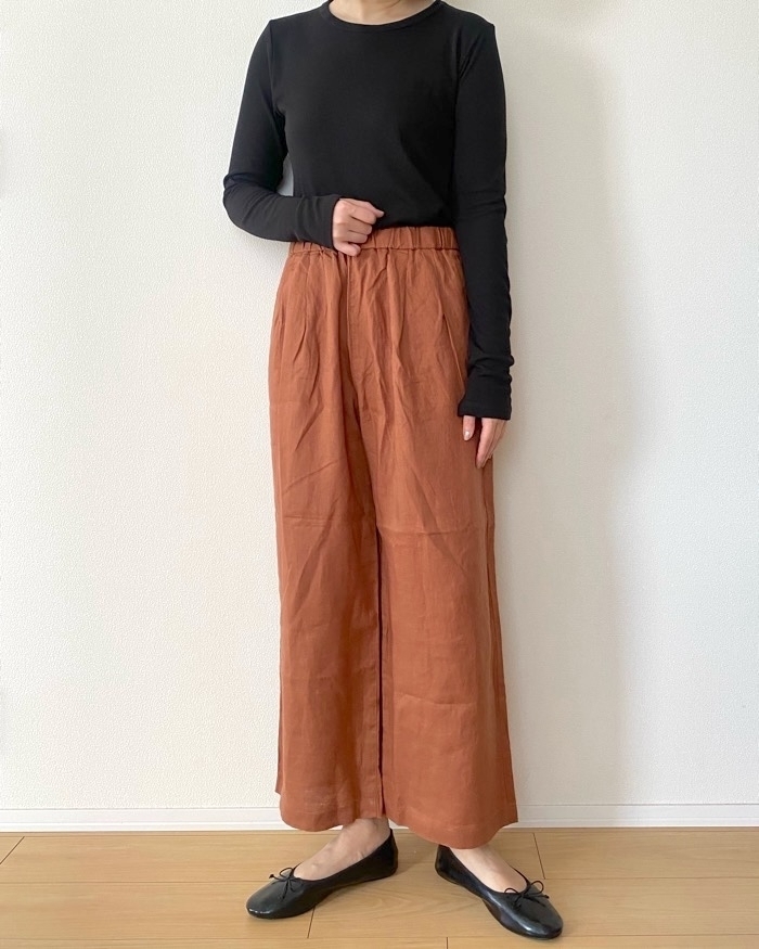 黒い長袖トップスにブラウンのワイドパンツを着た人物。シンプルでカジュアルなスタイル。
