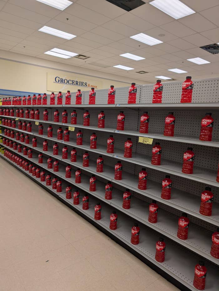 Store shelves are filled entirely with the same red condiment bottles, labeled "Groceries" above