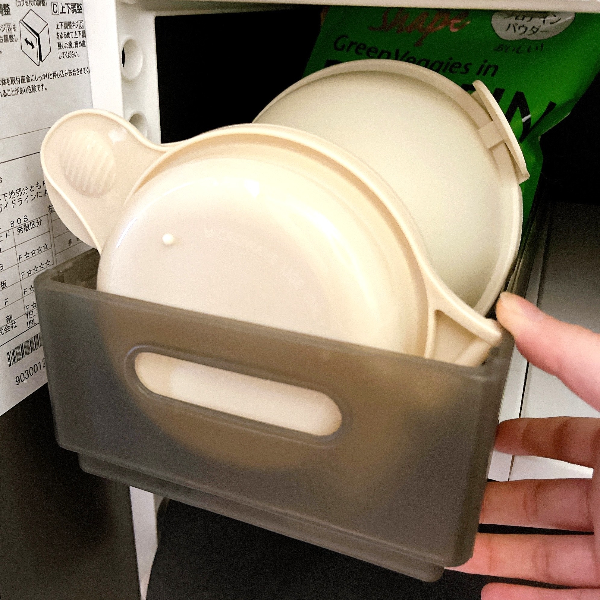 プラスチック容器がキッチン収納ボックスに収まっている様子。手がボックスを引き出そうとしている。