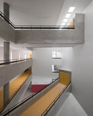 A modern, minimalist interior with concrete walkways and ramps, featuring geometric open spaces and natural light entering from skylights