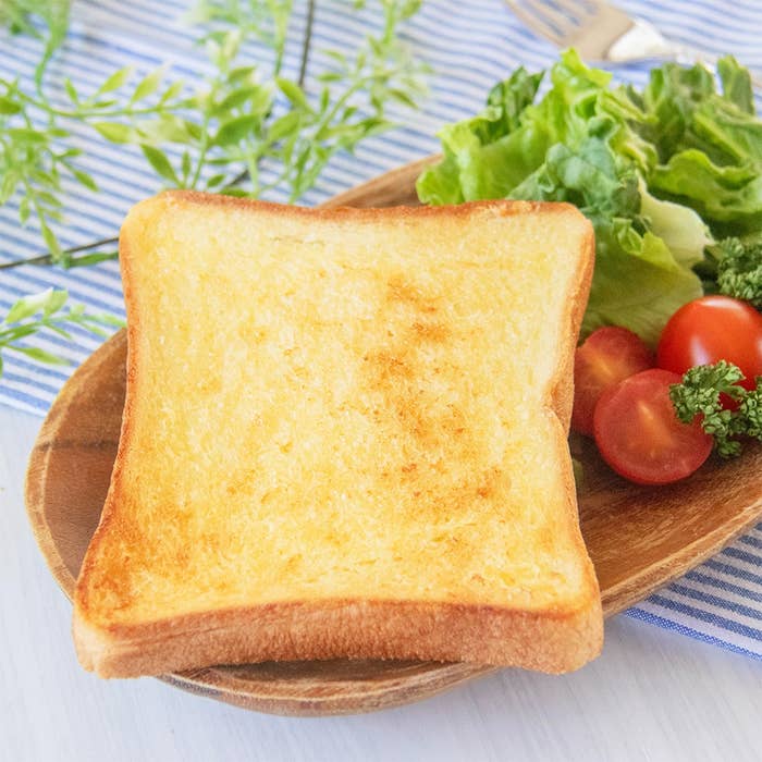 マヨネーズを塗って焼いたトースト、レタス、ミニトマトを盛った木製プレート。