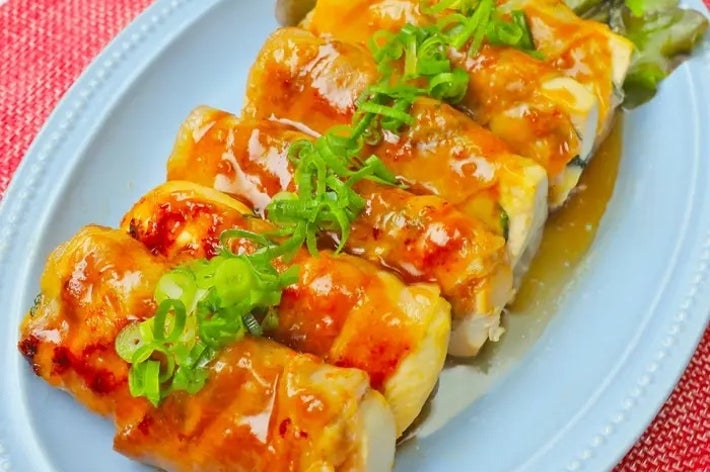 皿に盛られた照り焼きソースがかかったネギ添えの鶏肉料理。背景にはレタスが添えられている。