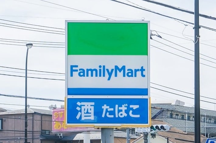 ファミリーマートの看板。「酒 たばこ」と記載されたサインが表示されています。住宅街の背景があります。