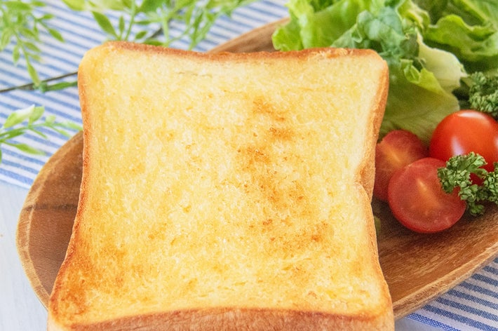 マヨネーズを塗って焼いたトースト、レタス、ミニトマトを盛った木製プレート。