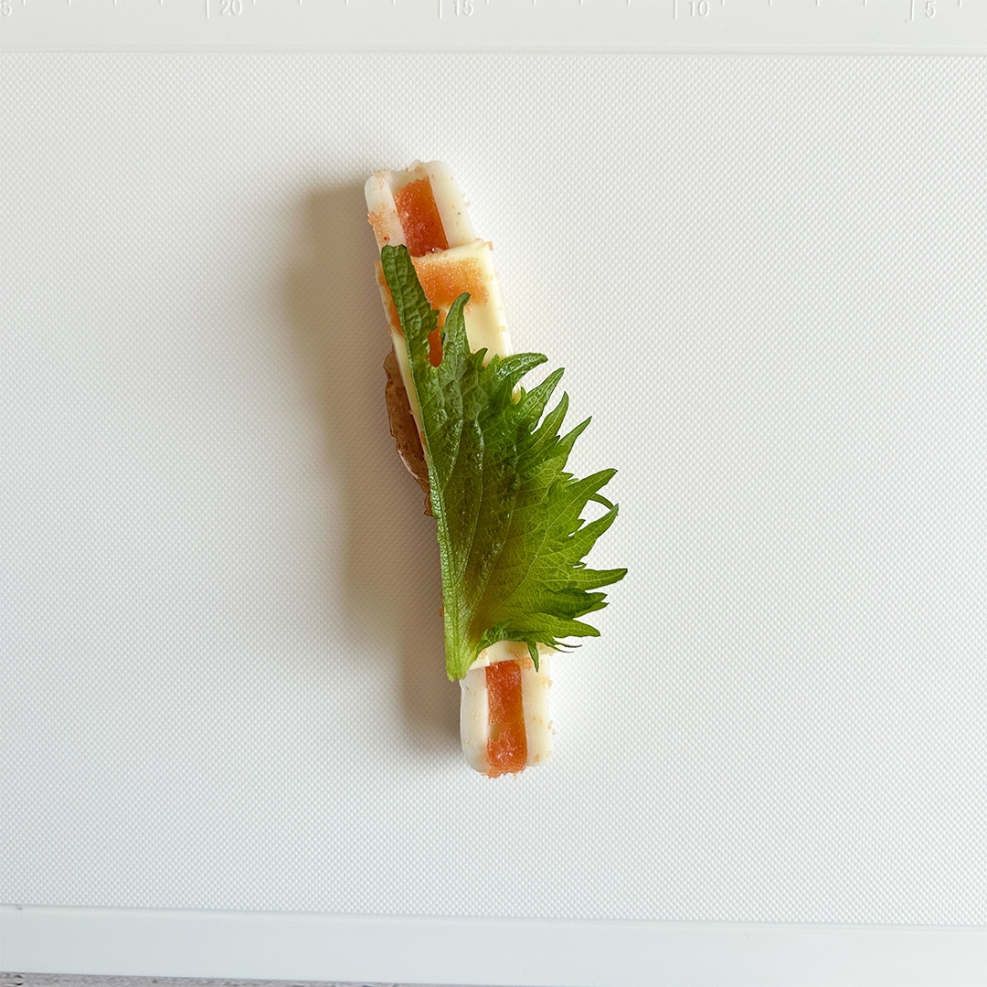 大葉と具材を載せた料理がまな板に置かれている。